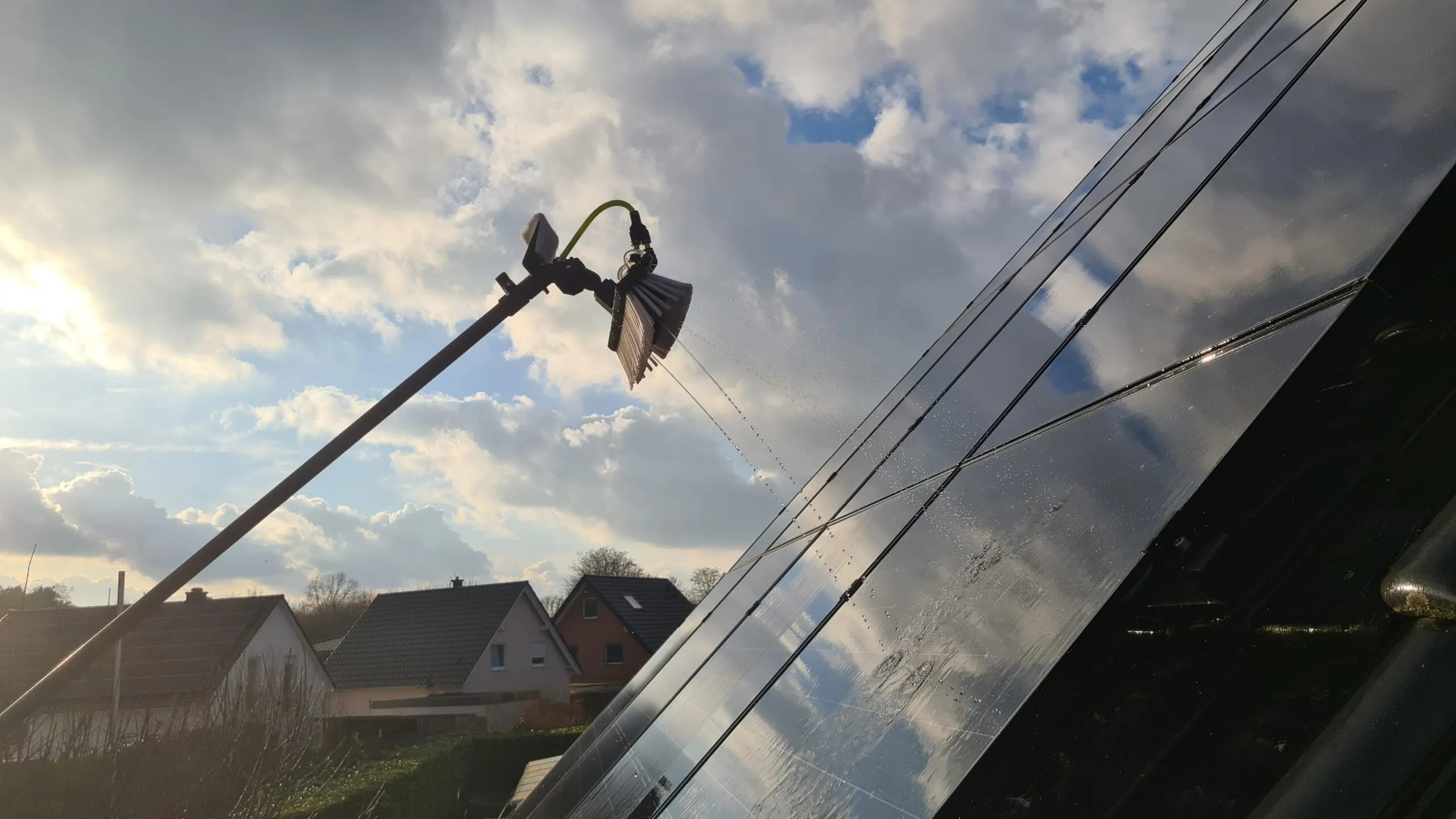Reinwasser-Bürste an einer Teleskopstange reinigt Solarmodule auf einem Dach in Verl