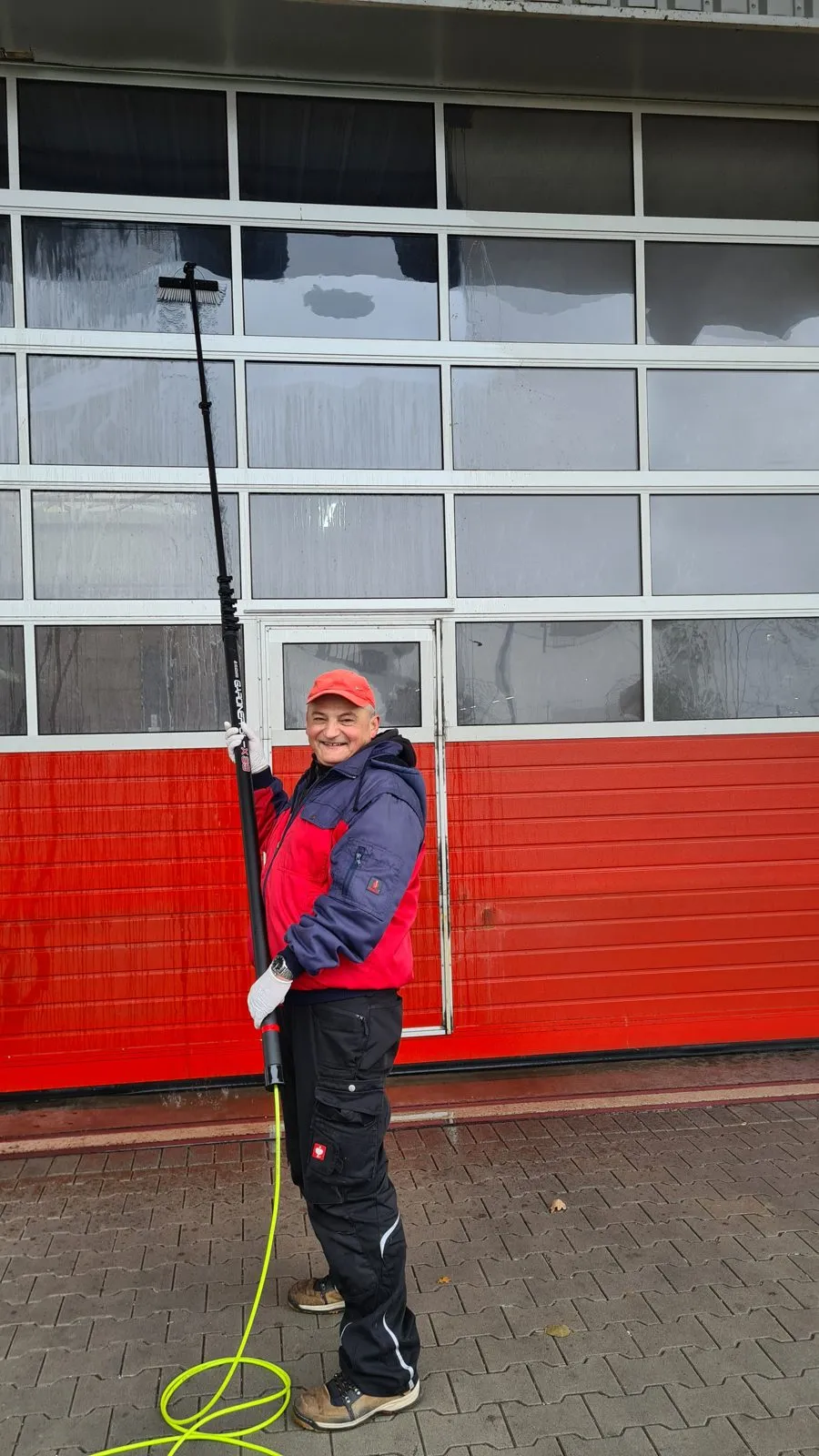 Inhaber Miroslav Petrovic mit der Reinwasser-Teleskopstange vor einem Hallentor
