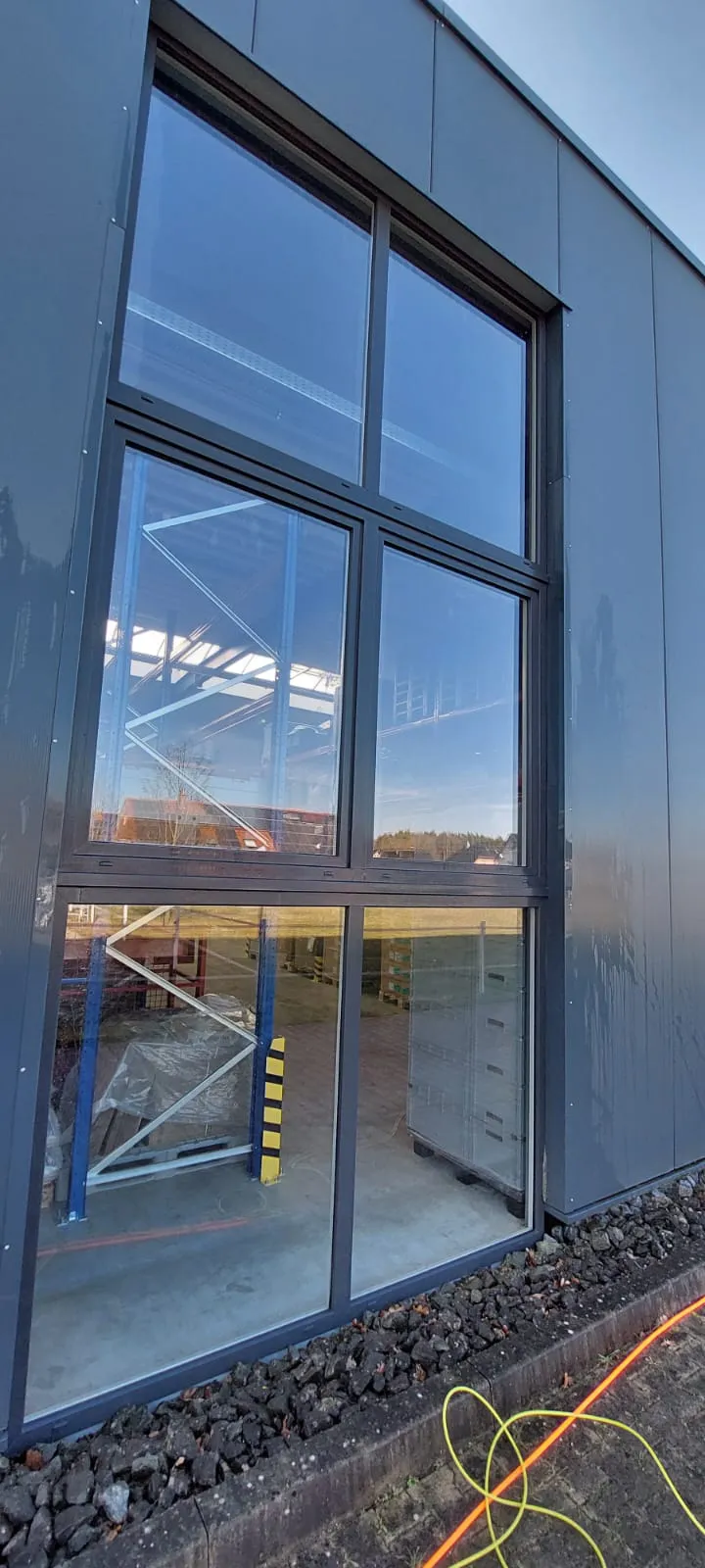Hohe Fensterfront einer Gewerbehalle nach der Reinigung mit Reinwasser