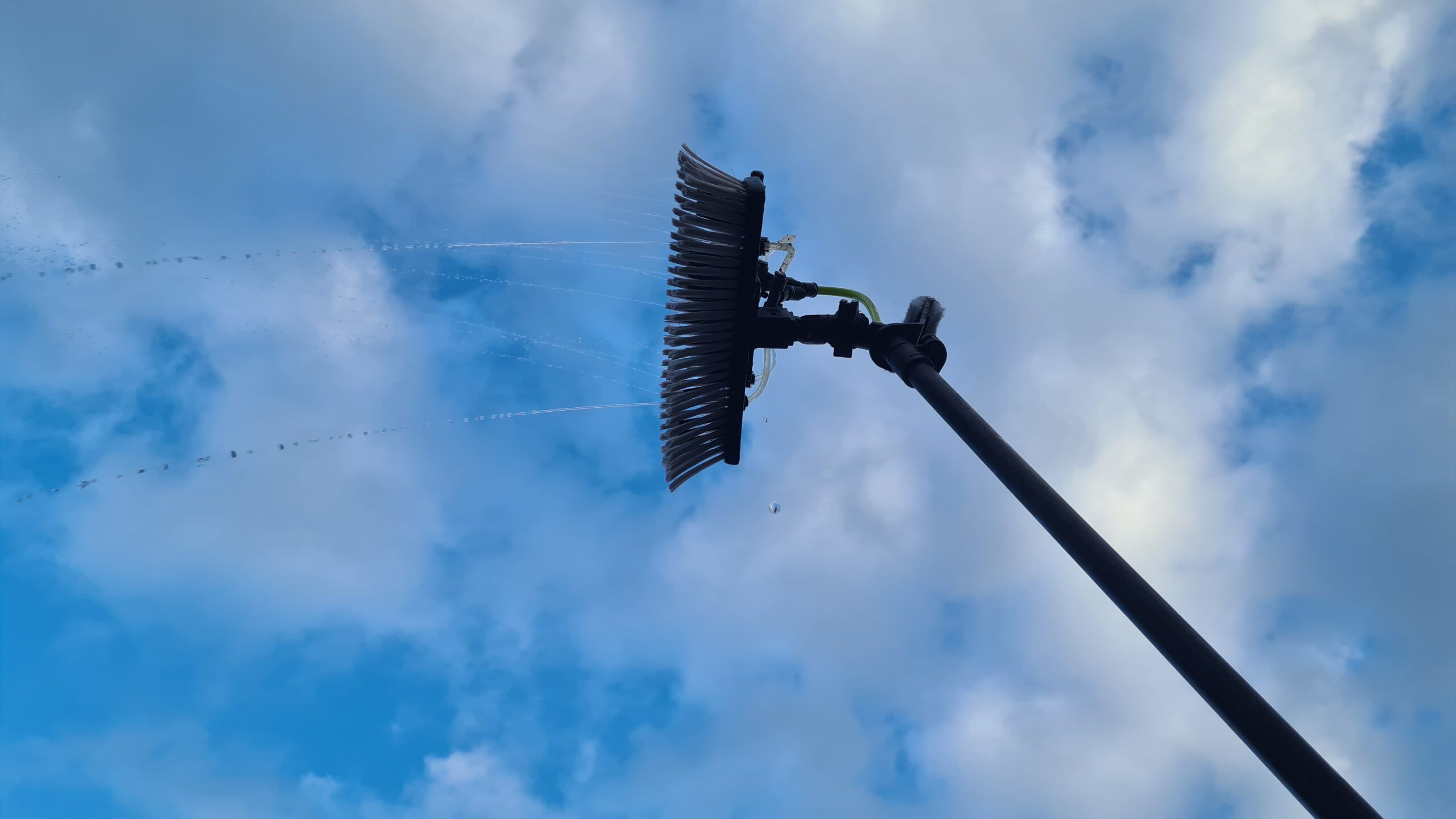 Reinwasser-Bürste an einer Teleskopstange vor blauem Himmel