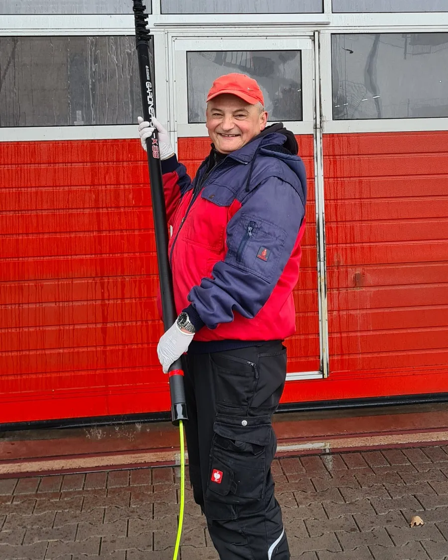 Inhaber Miroslav Petrovic mit der Reinwasser-Teleskopstange vor einem Hallentor